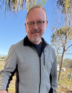 A smiling middle-aged white man outside on a sunny day